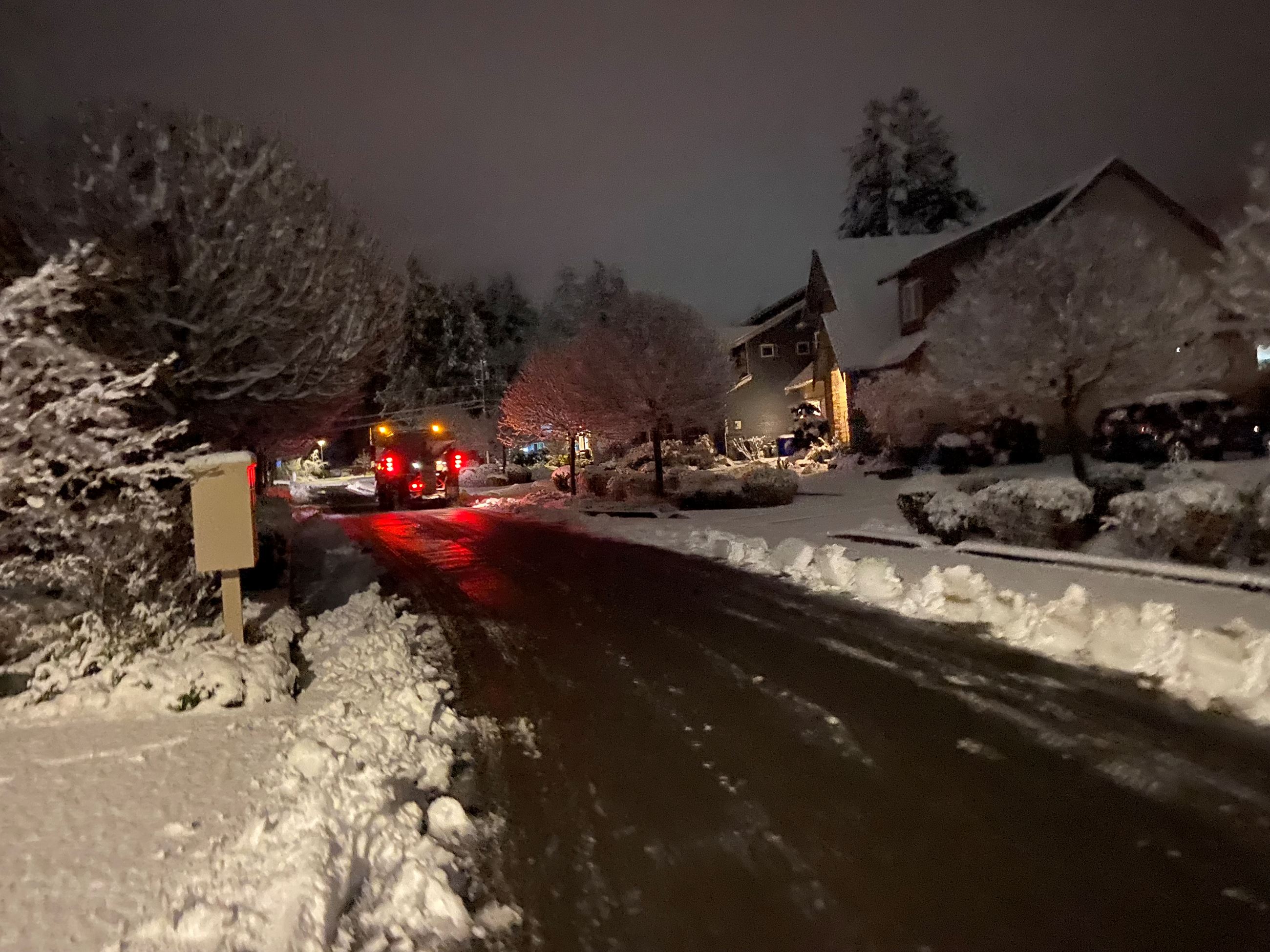 A snowplow plowing roads at night